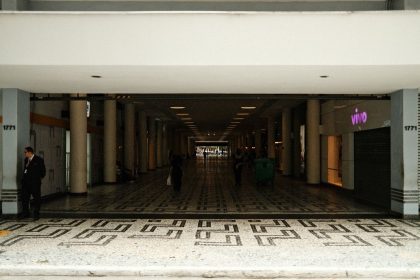 Corredor amplo de um shopping center moderno, com pessoas caminhando sob iluminação interna.