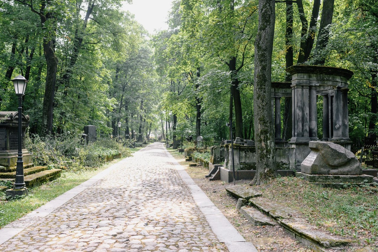 Caminho de pedras entre árvores e túmulos em um cemitério ao ar livre