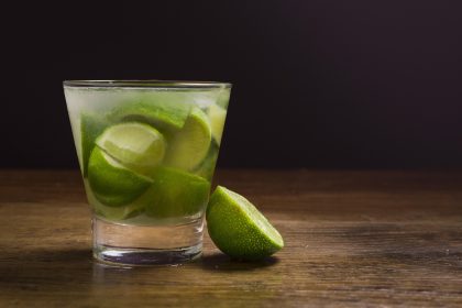 Caipirinha brasileira com limão e cachaça servida em um copo, acompanhada de uma garrafa.